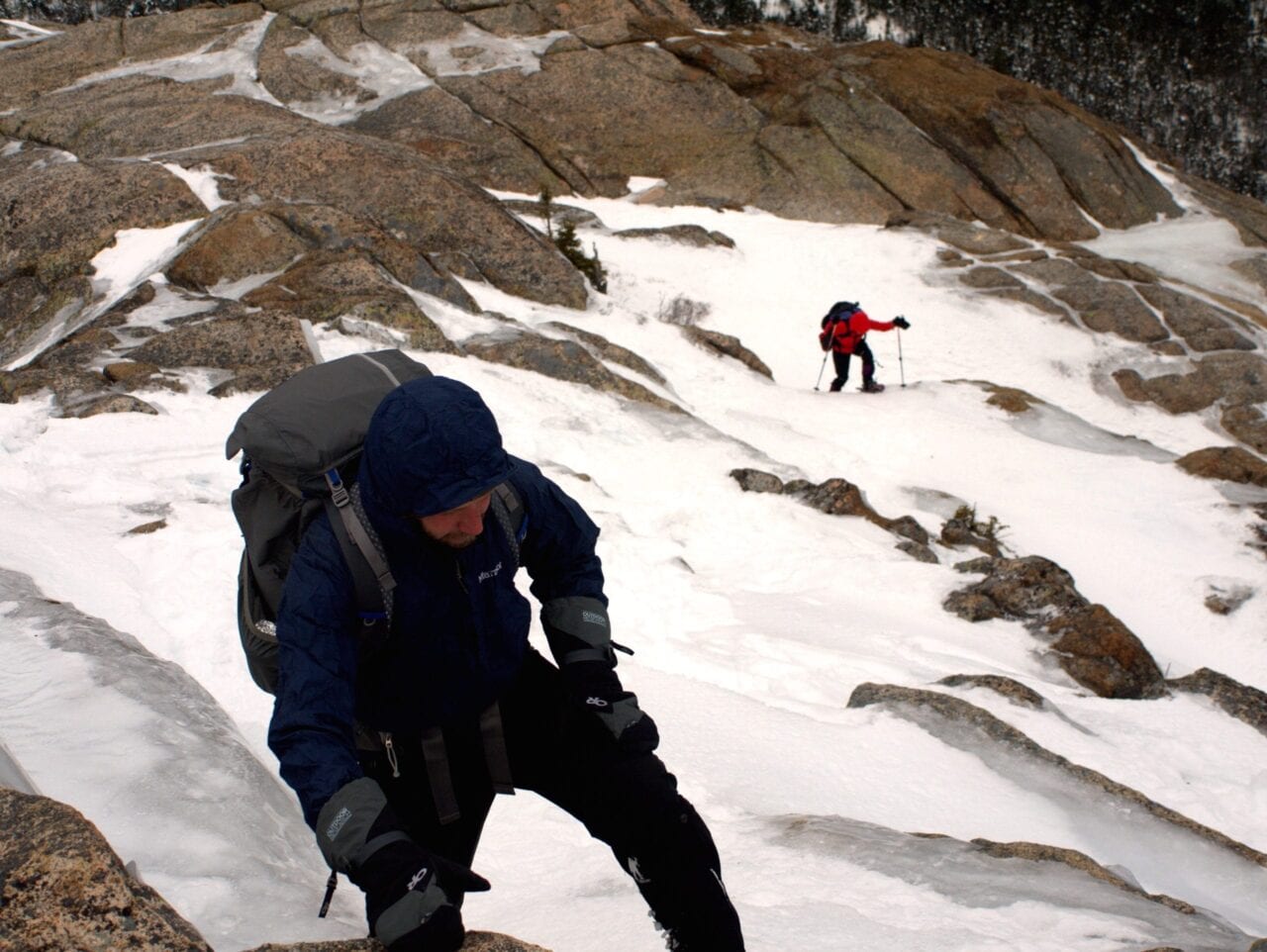 Two hikers climb through a snow field.