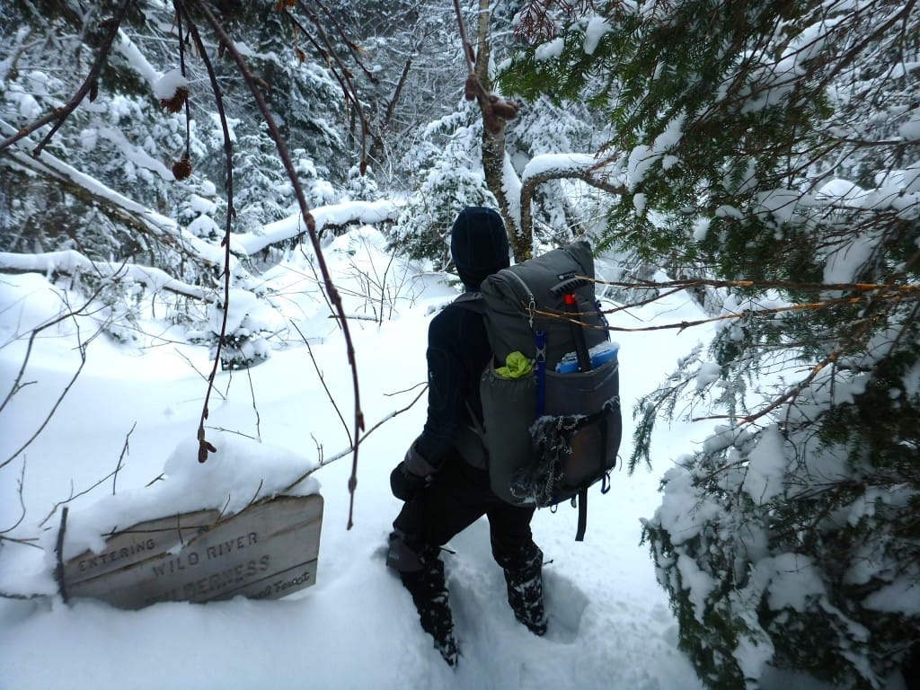 A hiker wades through deep snow.