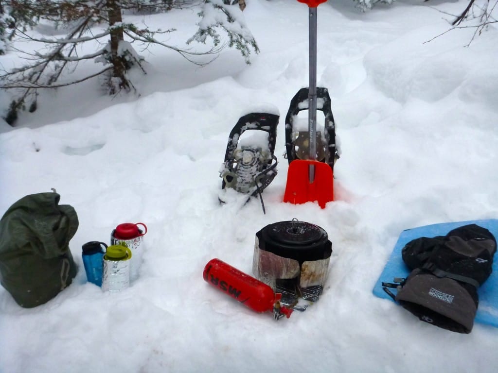 Hiking gear sits on the snowy ground.