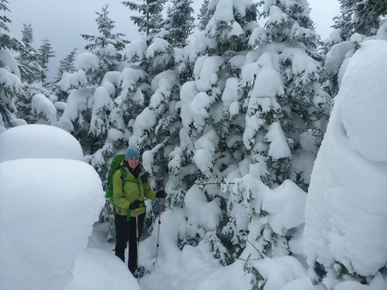 A hiker walks down a snow-covered trail.