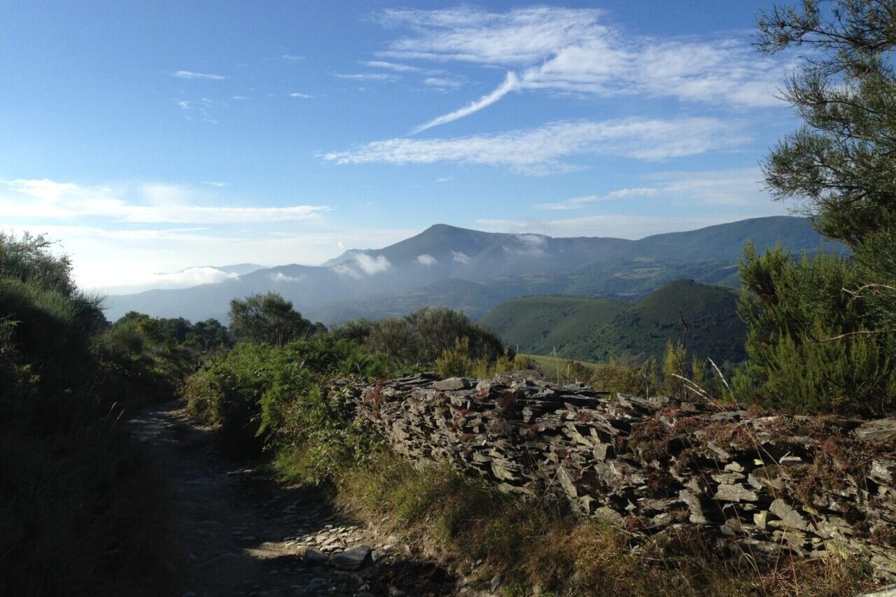 A trail looks over distant mountains and blue skies.