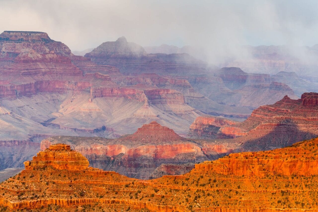 The Grand Canyon is lit with a red glow and mist.