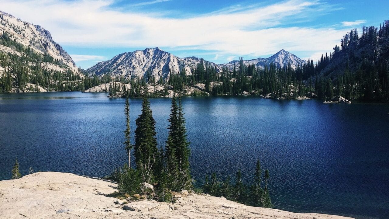 A vibrant blue alpine lake is surrounded by rocky mountain peaks.