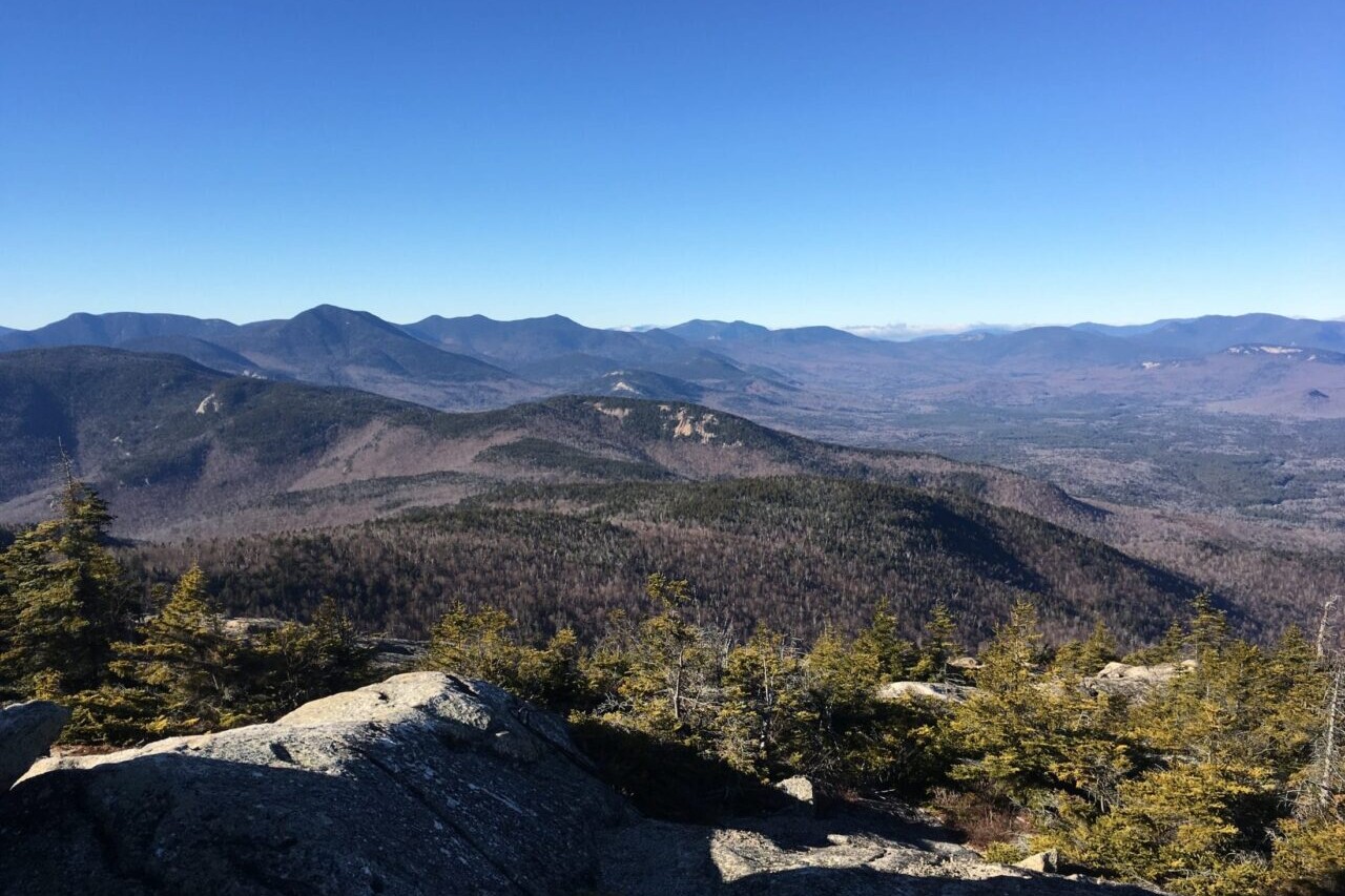 A rocky ridge overlooks distant mountains.