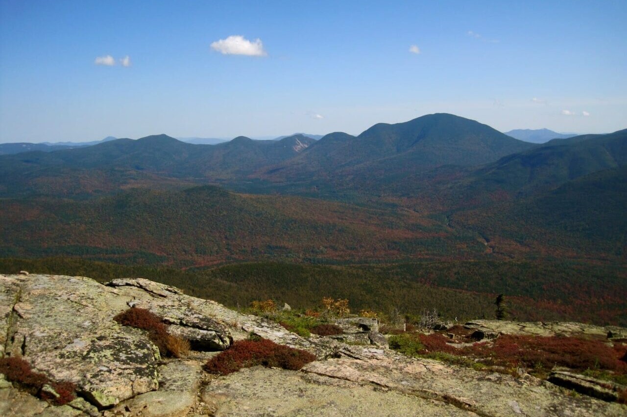 A rocky ridge overlooks distant mountains.