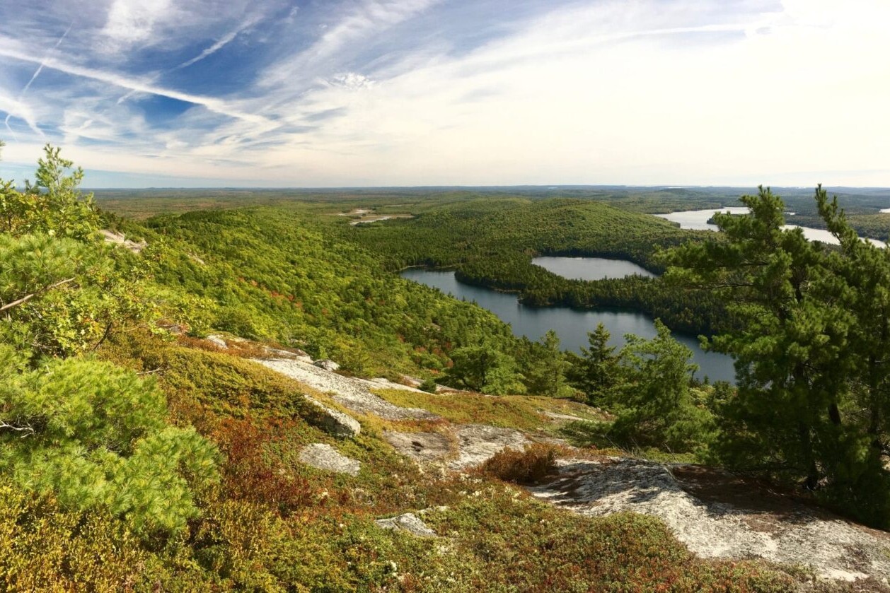 A view overlooks a green valley and clear lakes.