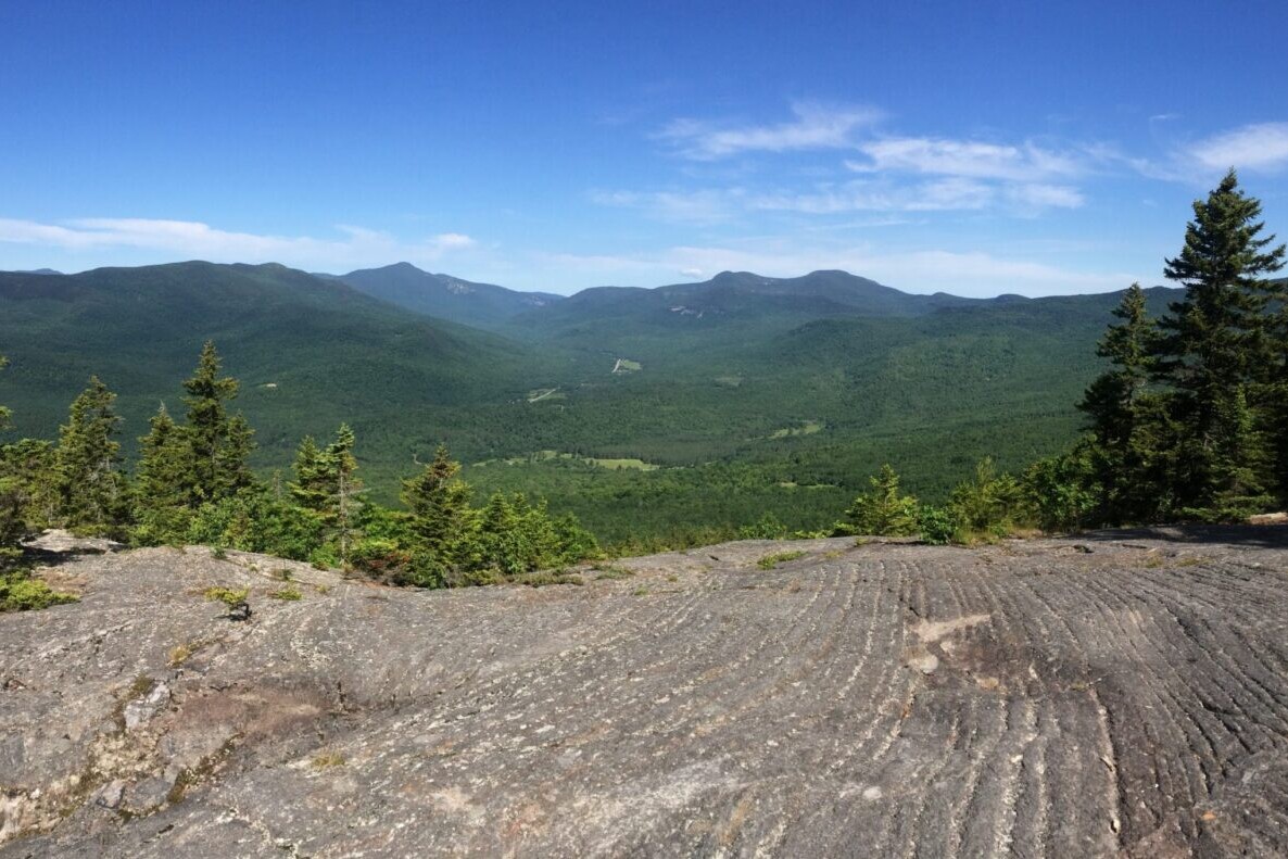 A rocky ridge overlooks distant mountains.