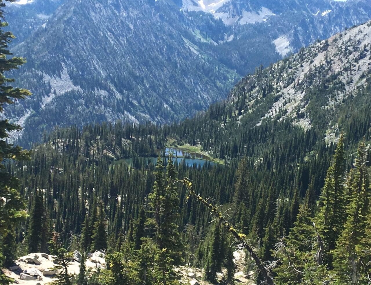 A view from a distant mountain pass shows a lake shaped like a heart.