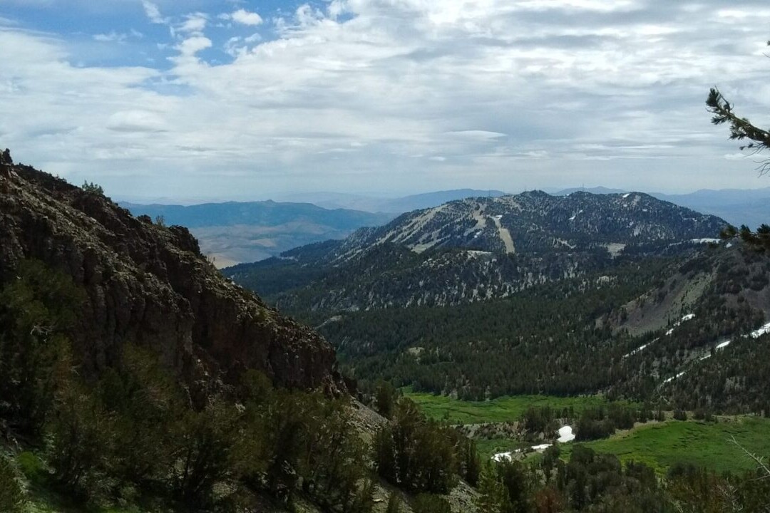 A view overlooks meadows and distant mountains.