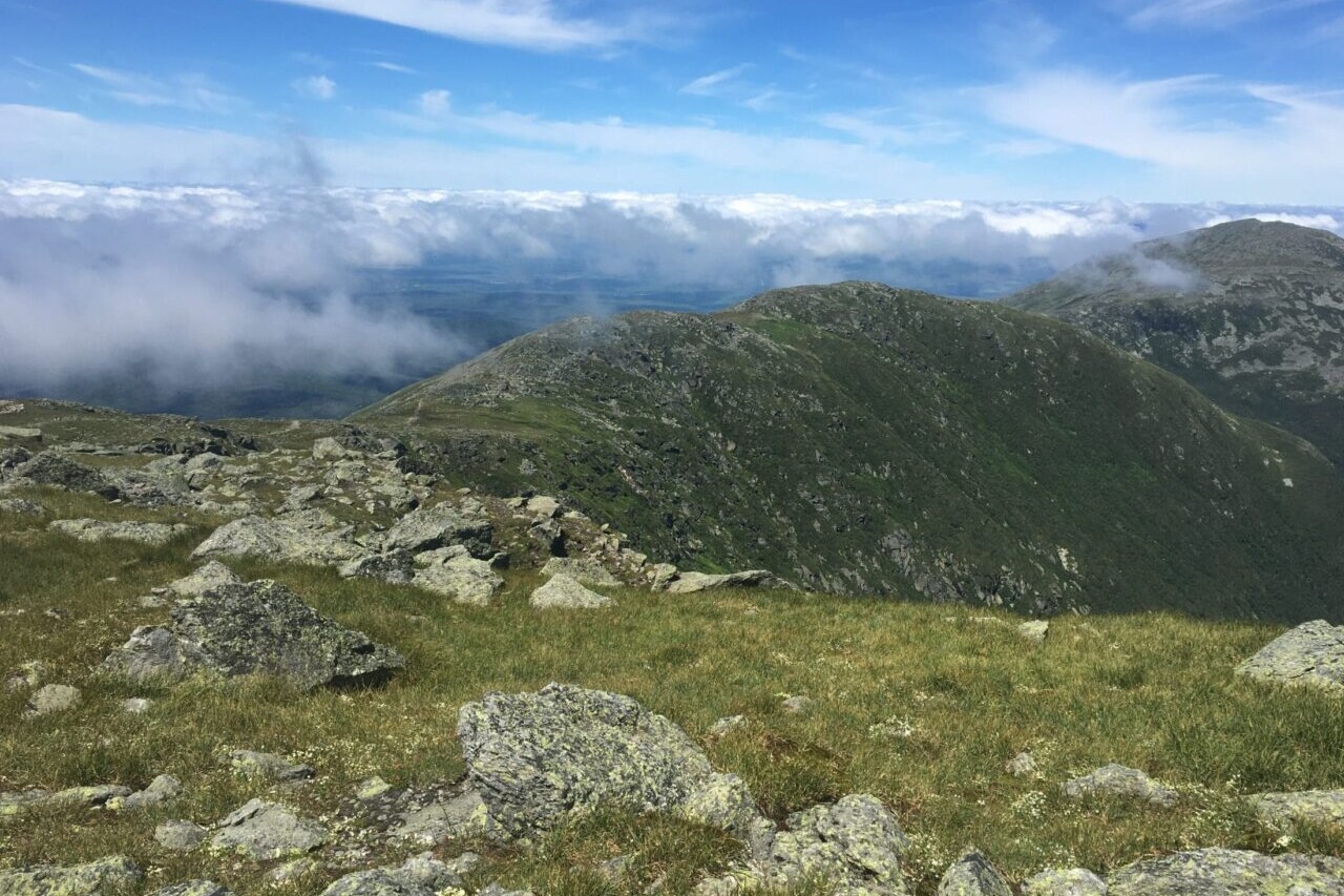 A green and rocky ridgeline leads into the distance against a blue sky.