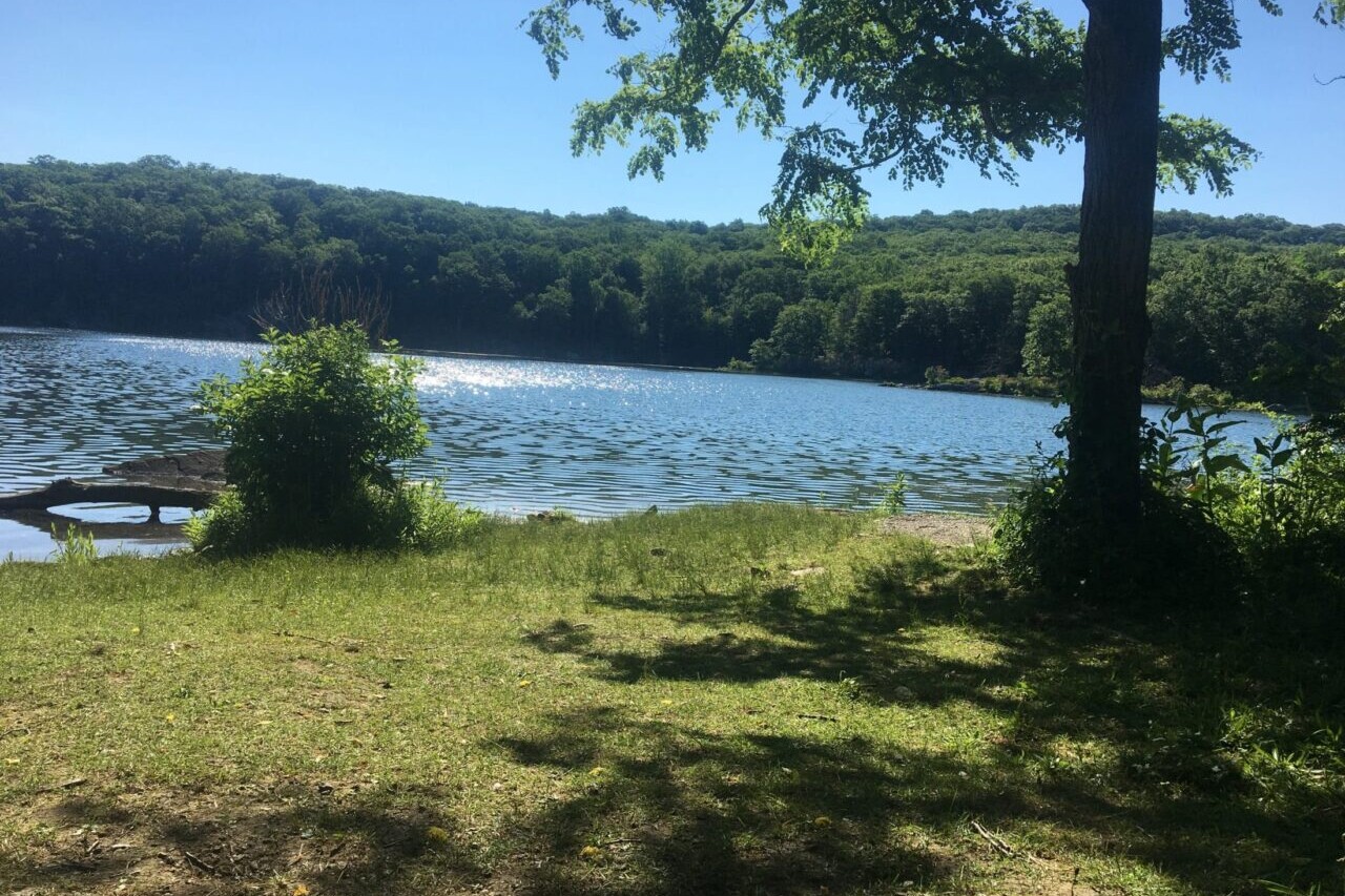 A blue lake is surrounded by rolling green hills.