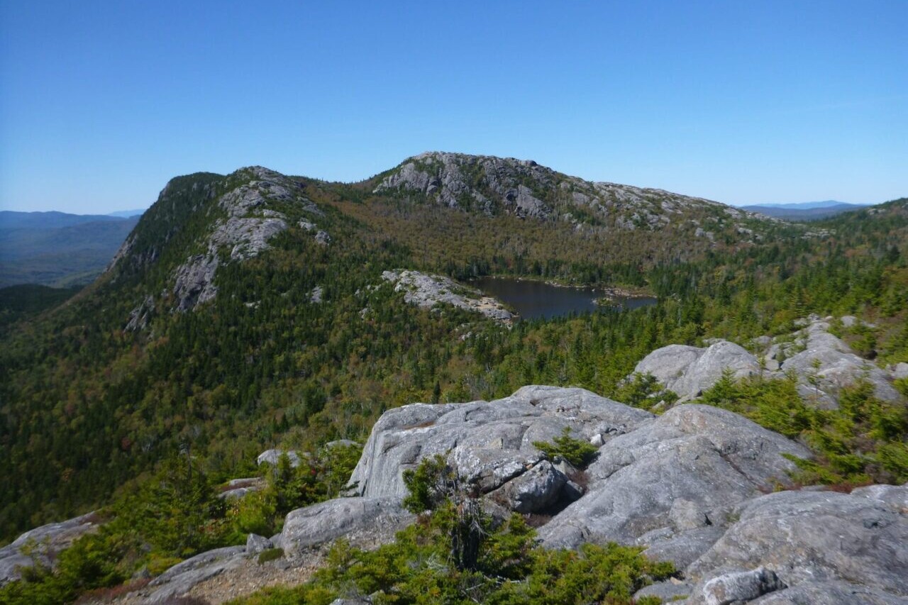A rocky ridge overlooks a nearby mountain and lake.