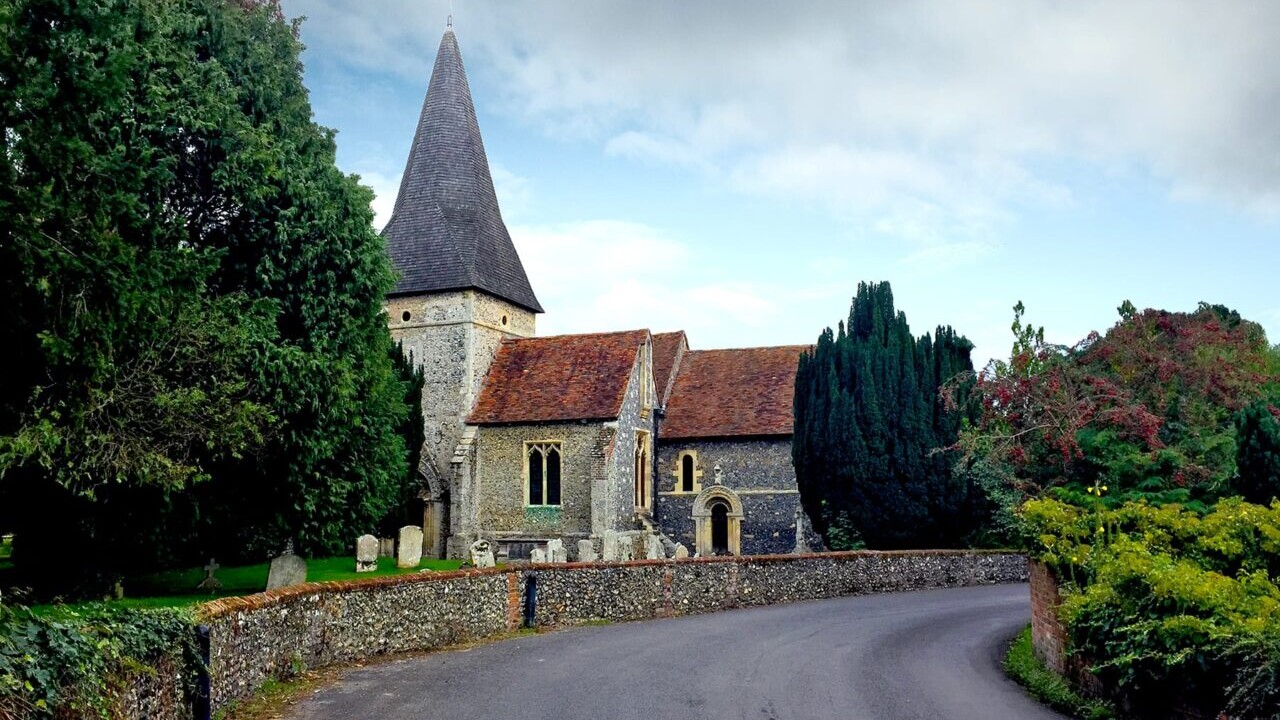 A paved road leads to an old stone church on England's South Downs Way.