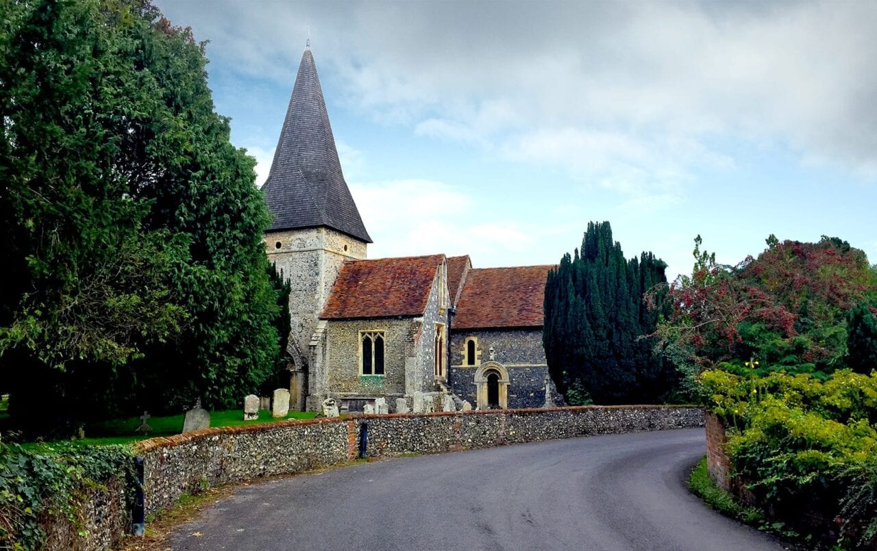 A paved road leads to an old stone church on England's South Downs Way.