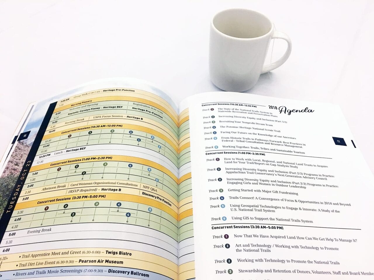 A conference program and a coffee mug sit on a white table.