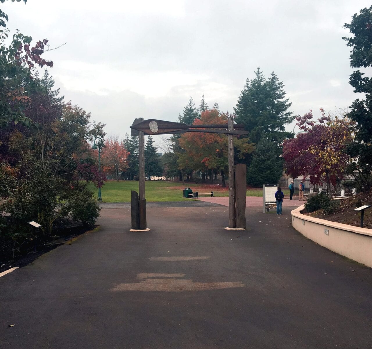 A wooden archway with Native American art sits in the middle of a sidewalk.