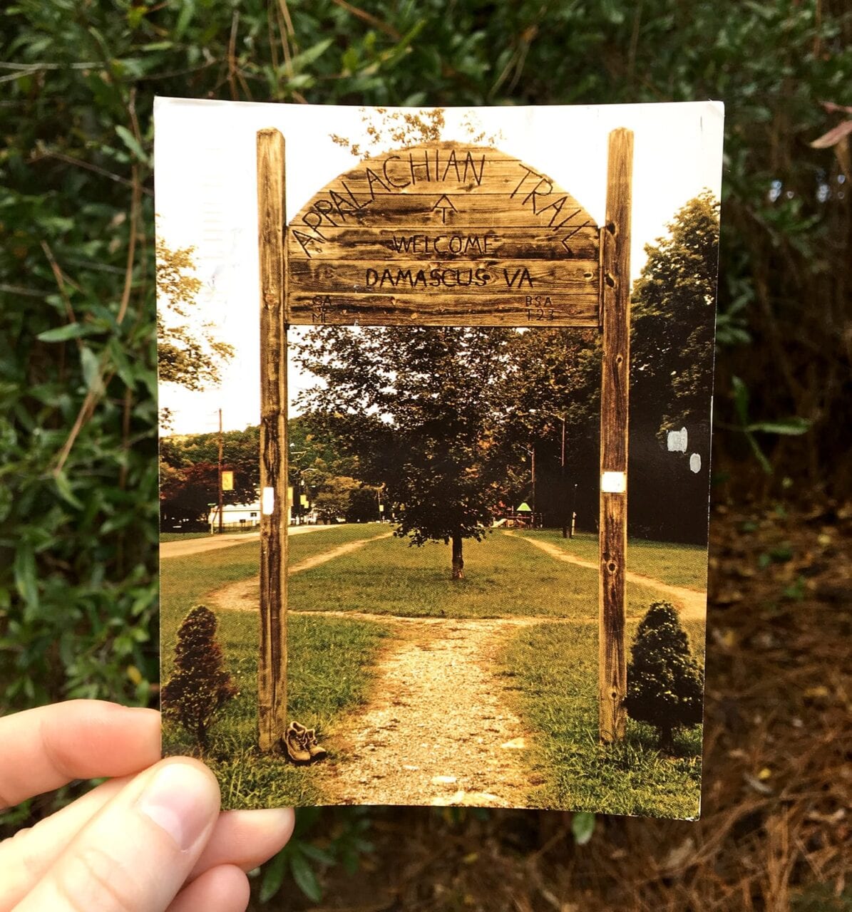 A person holds a postcard from the Appalachian Trail.