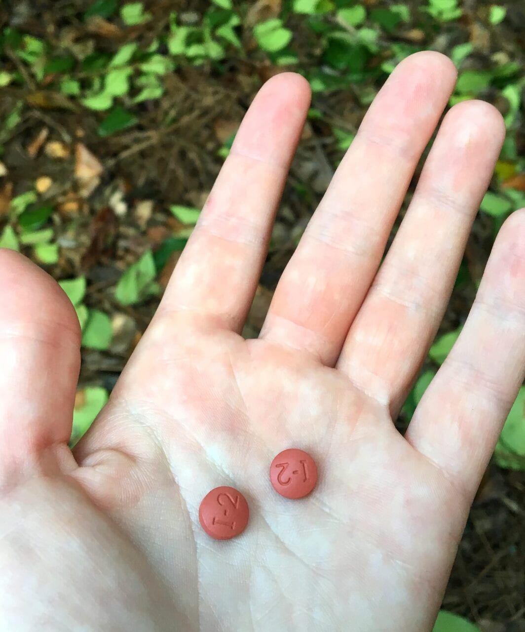 a person holds two ibuprofen pills.