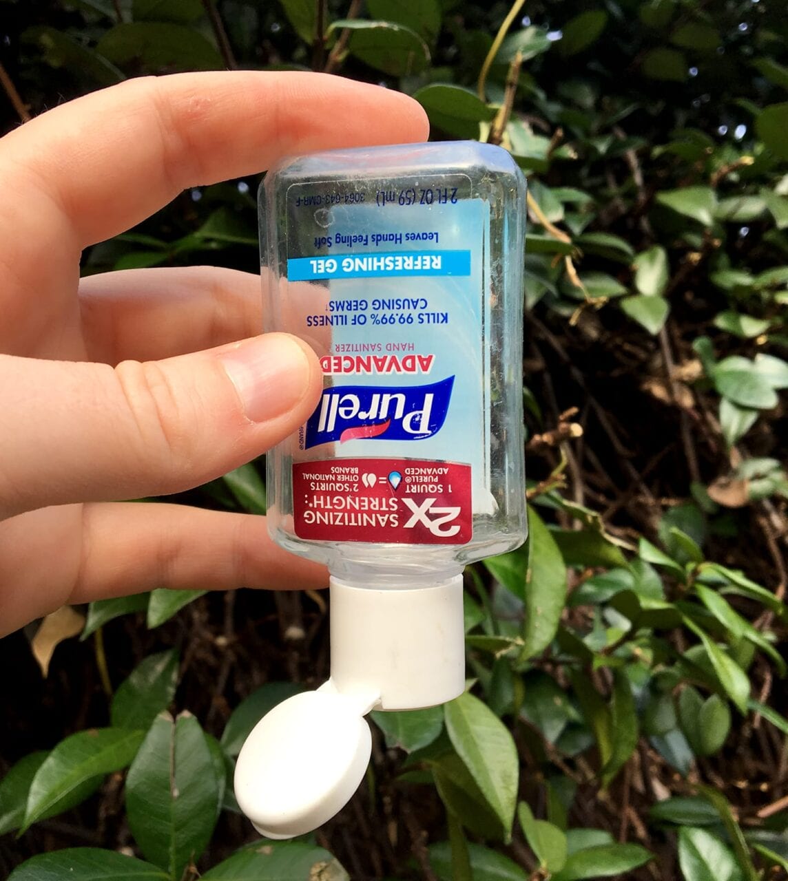 a person holds an empty bottle of hand sanitizer/