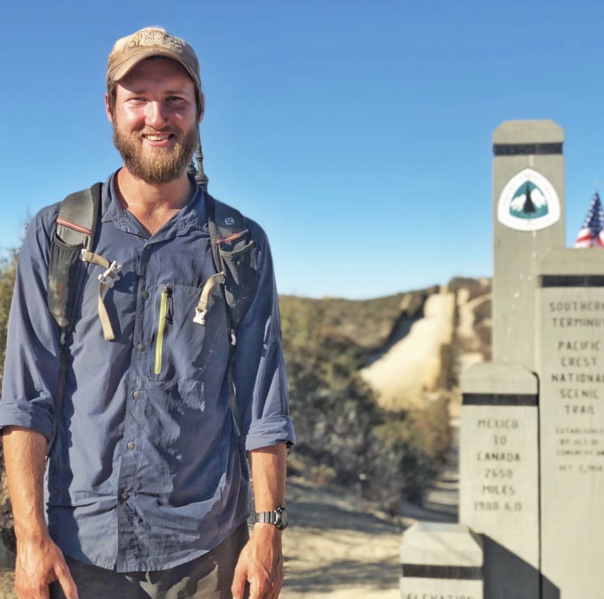 A thru hiker poses by the southern PCT terminus.