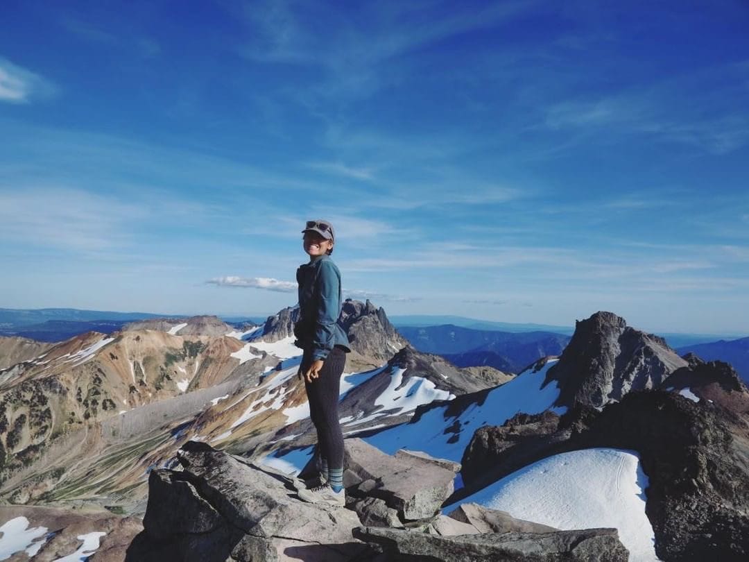 A thru hiker stands on top of a mountain.