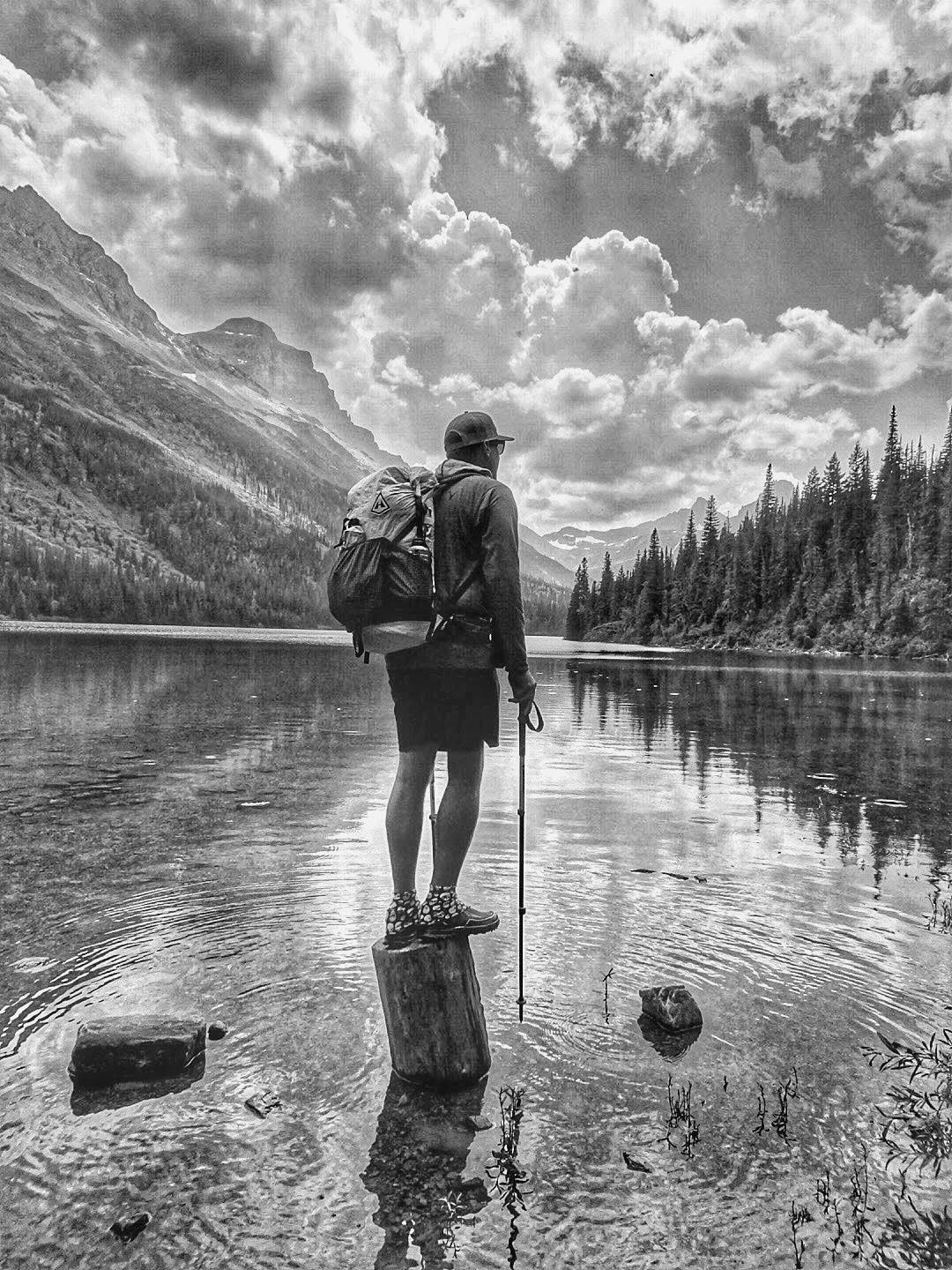A man standing on a log in a lake.