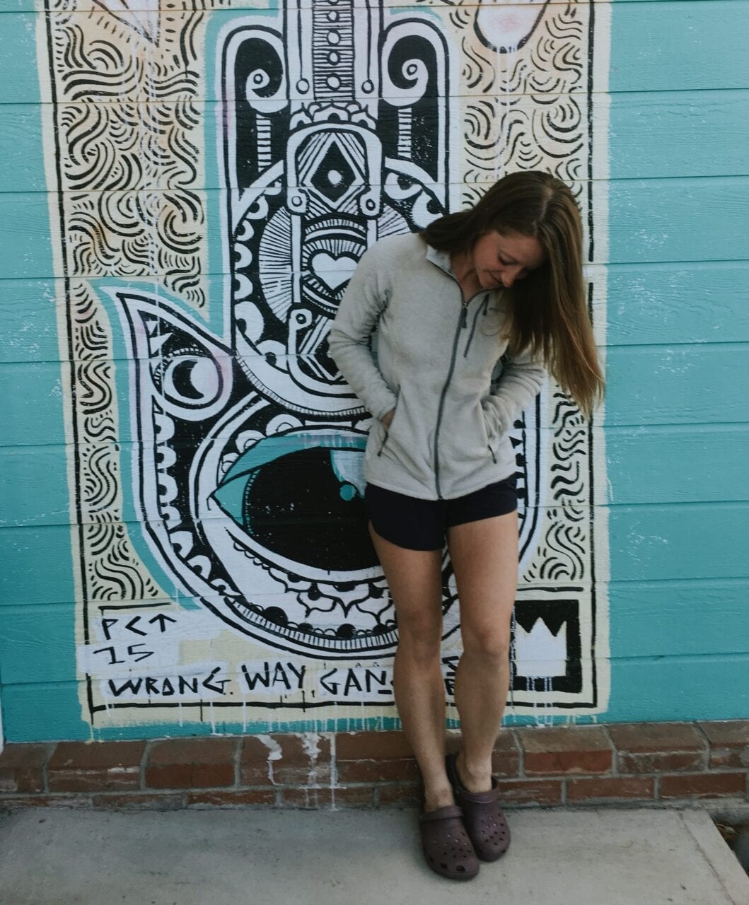 A woman posing against a wall with street art.