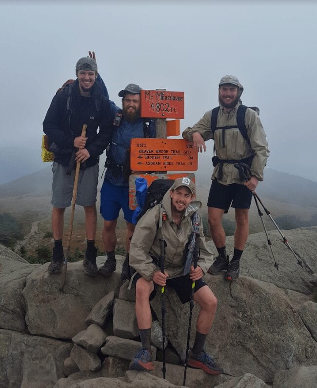 A group of guys hiking pose by a trail sign on the Appalachian Trail.