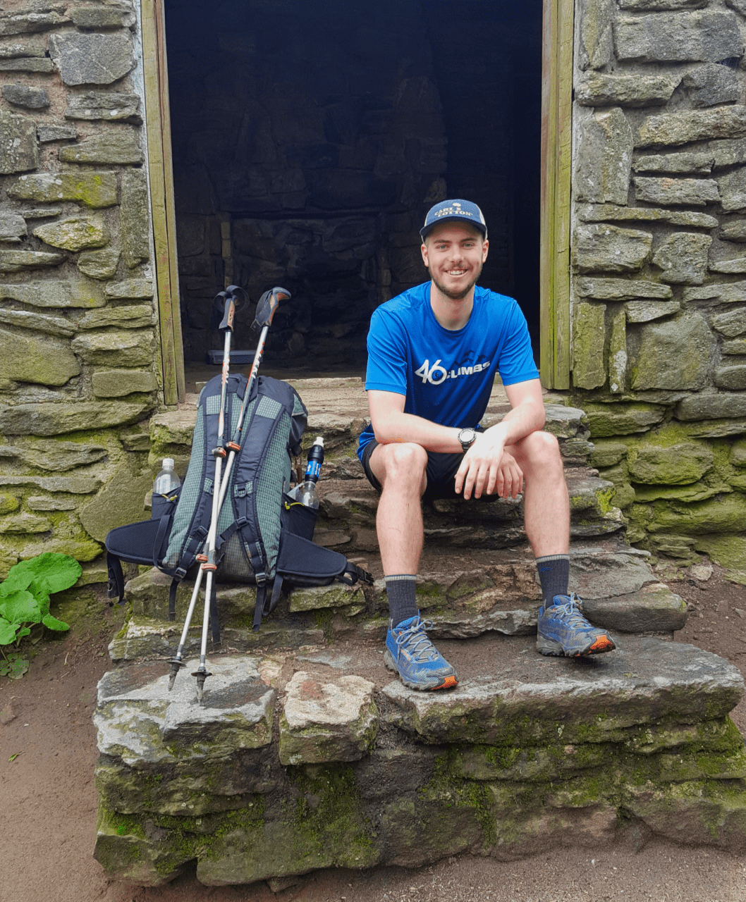 A guy hiking the Appalachian Trail sits on the steps of a building with his backpack next to him.
