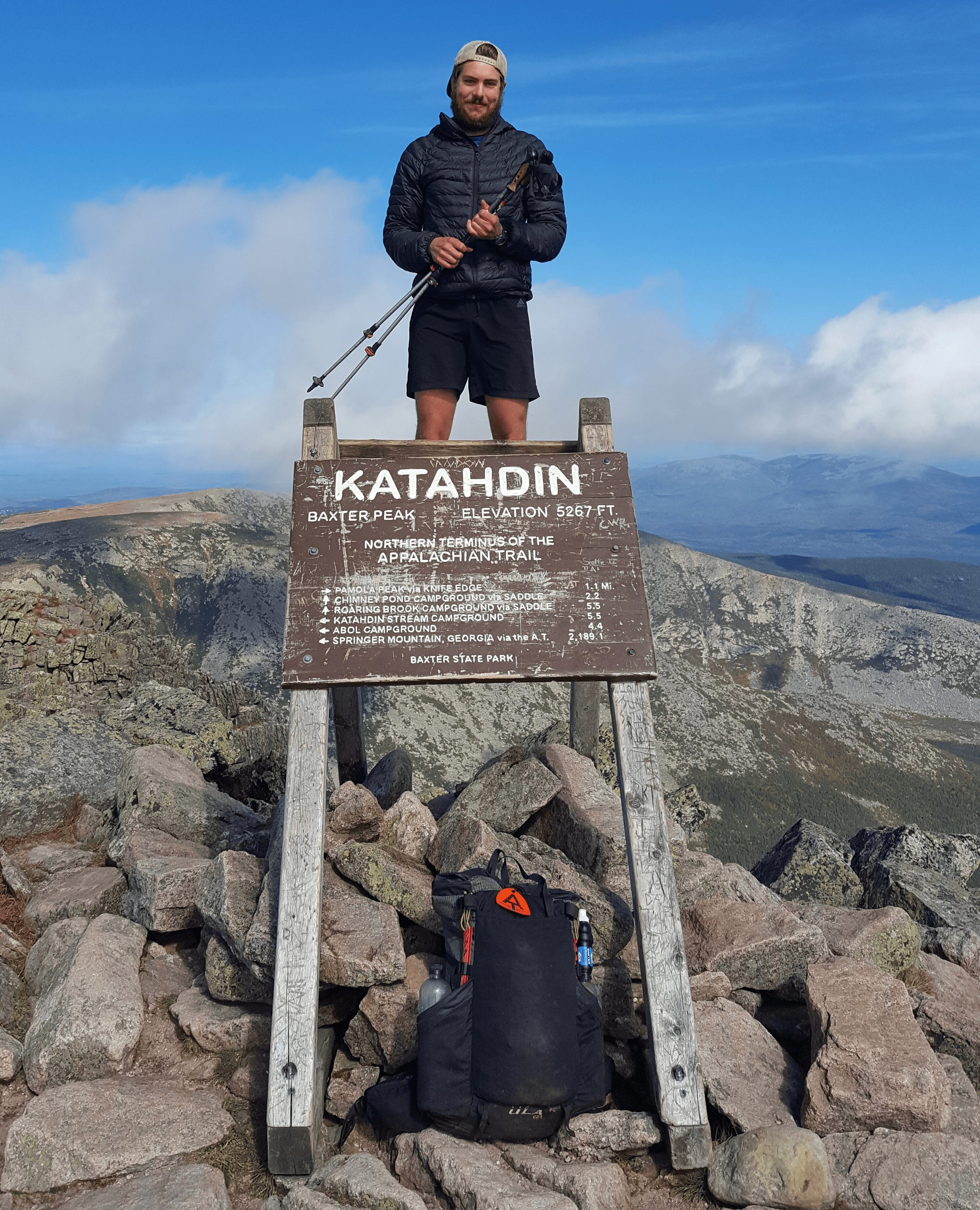 A hiker stands on the Mount Katahdin sign on the Appalachian Trail.
