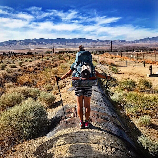 A woman hiker standing on an aqueduct.