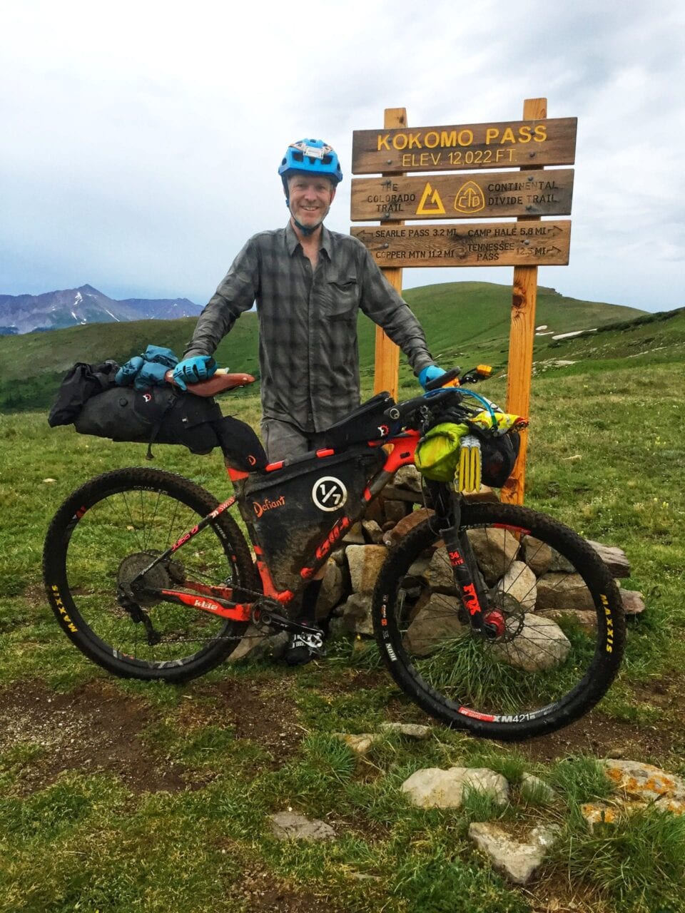 A biker stands with his bike next to a Colorado Trail sign.