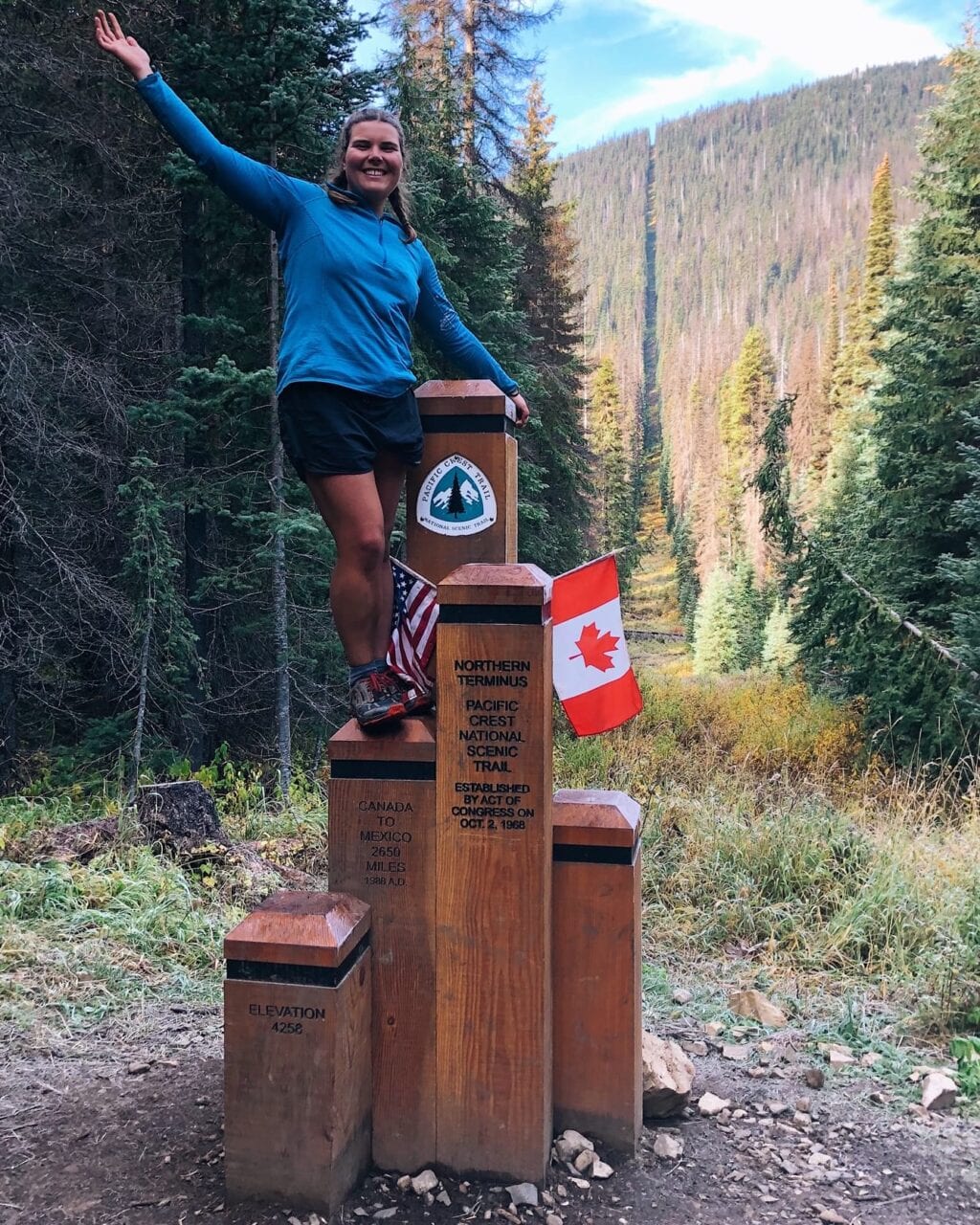 A woman hiker standing on the northern terminus of the Pacific Crest Trail.
