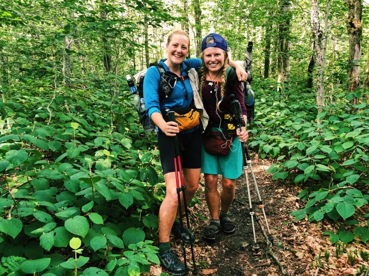 Two women hiking in a very green forrest.