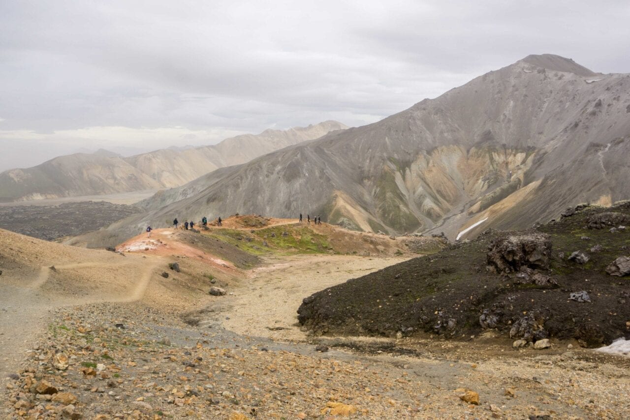 People hiking far in the distance on rocky mountain.