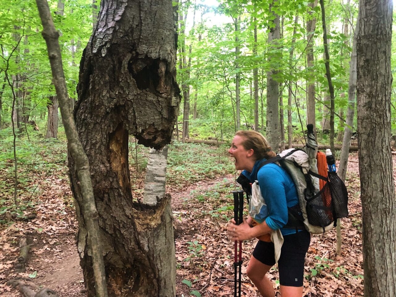 A woman looking at a tree that looks like it has a scary face.