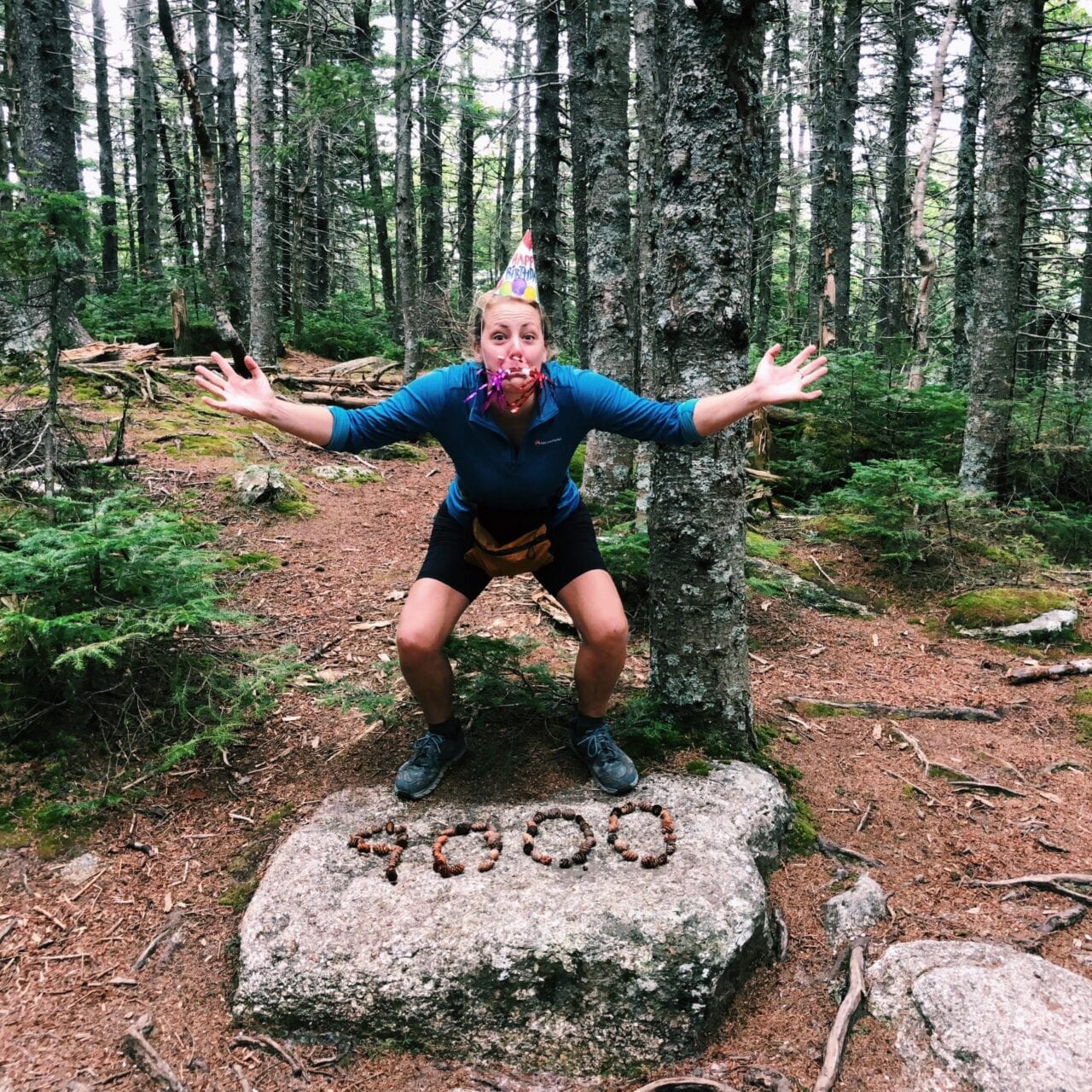 A woman with a party hat standing on a rock on the Appalachian Trail.