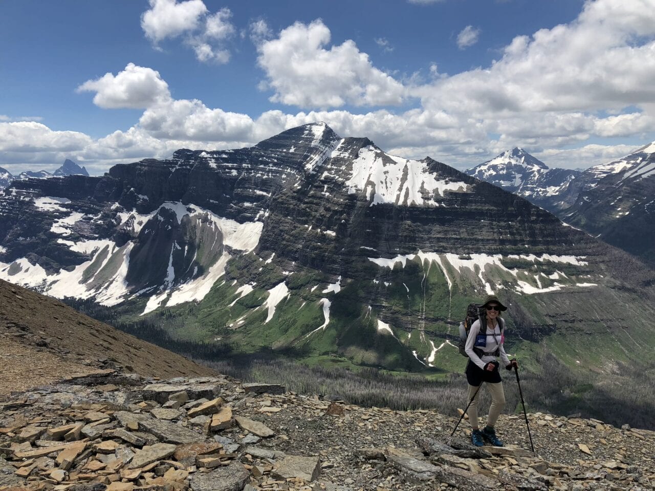 A hiker standing with a snow-covered mountain in the distance.