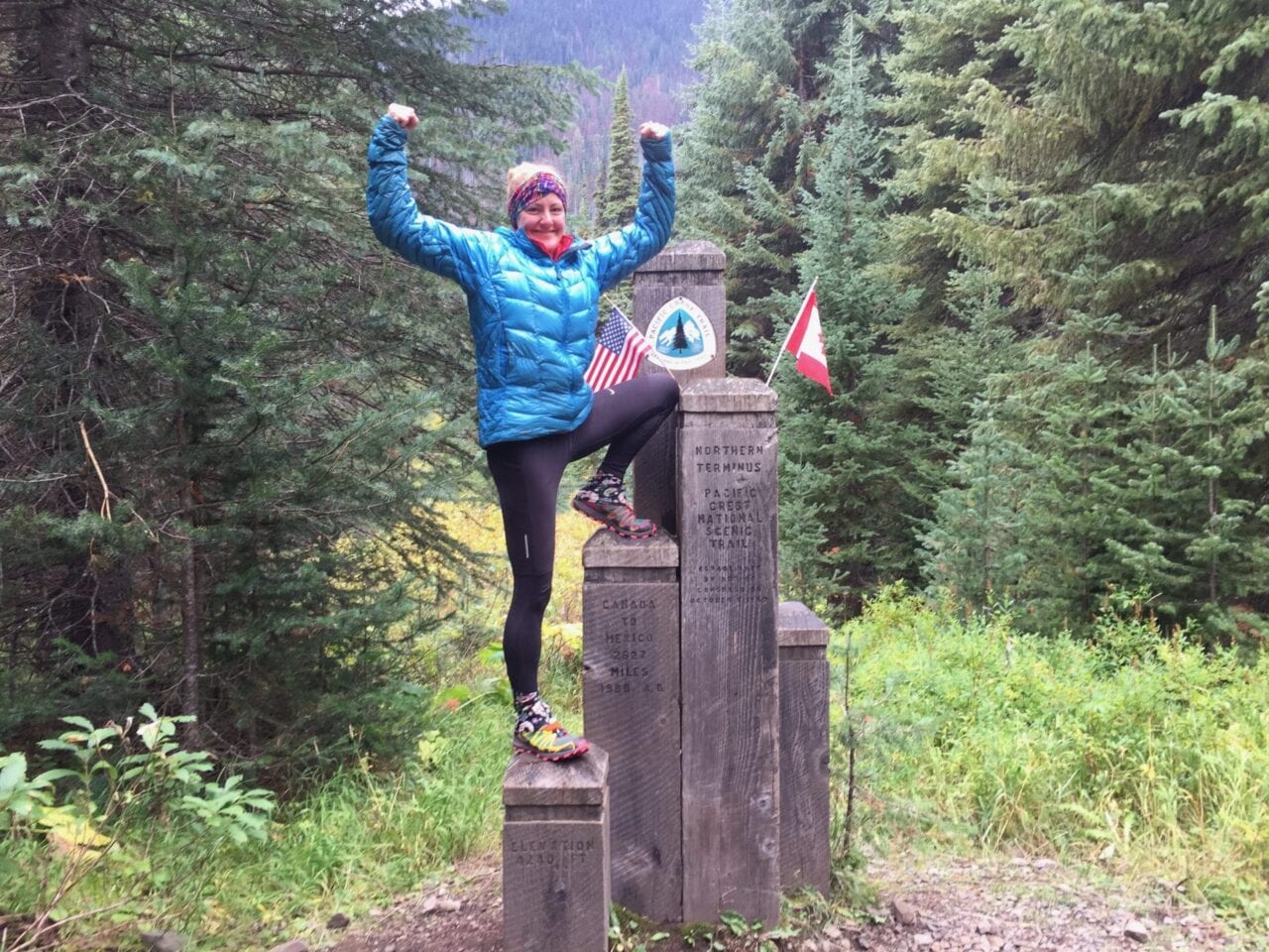A woman standing on the northern terminus of the Pacific Crest Trail.