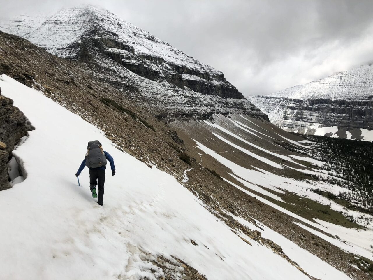 A hiker on a snowy mountain hillside.