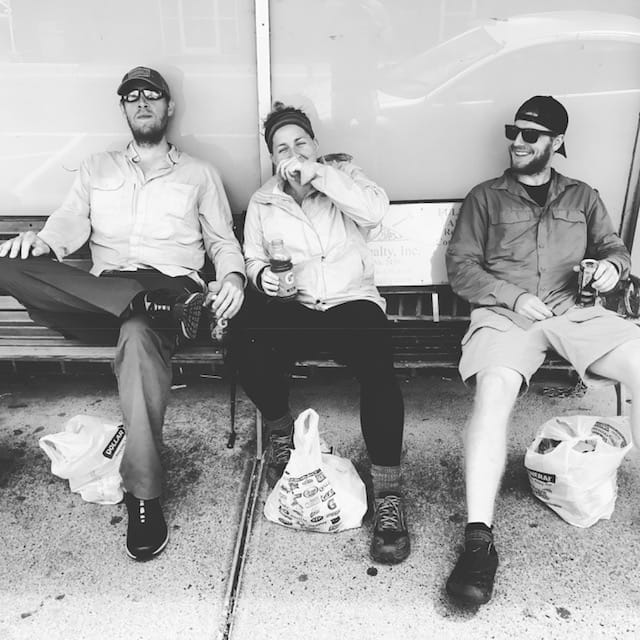 Hikers sitting on a bench laughing.