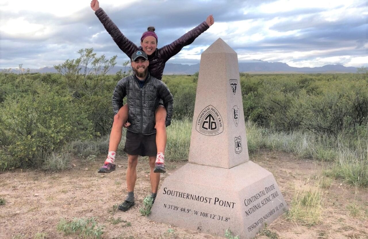 A man giving his wife a piggy back ride next to the Continental Divide Trail terminus.