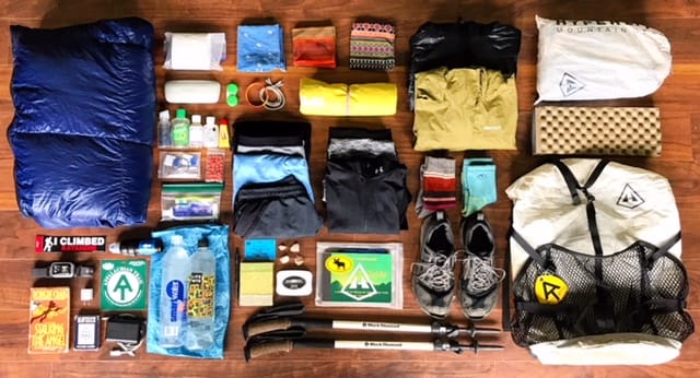 A hiker lays out all of her hiking gear on the floor to display everything she's brining on her thru-hike.