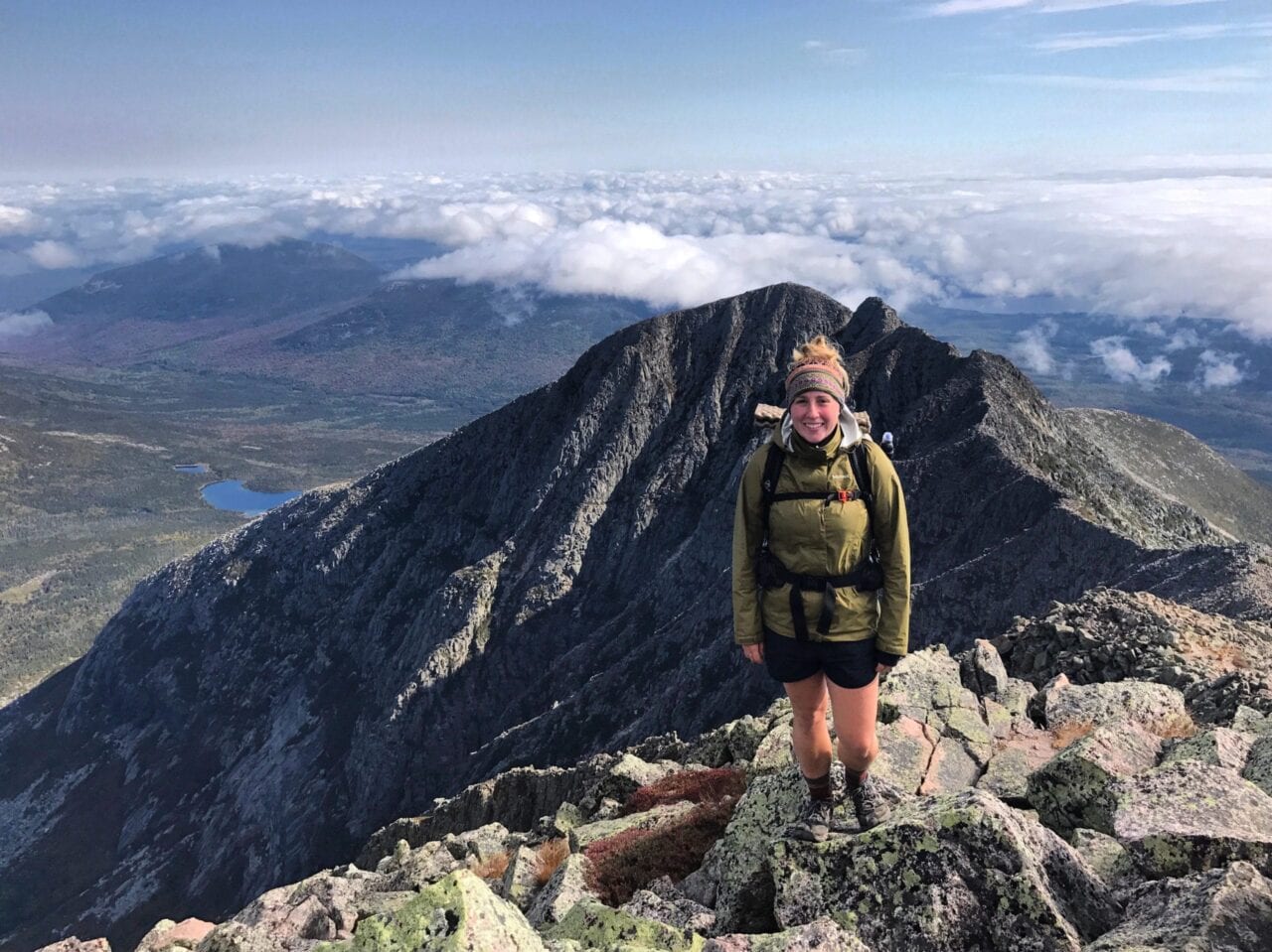 A woman standing on a mountain peak.