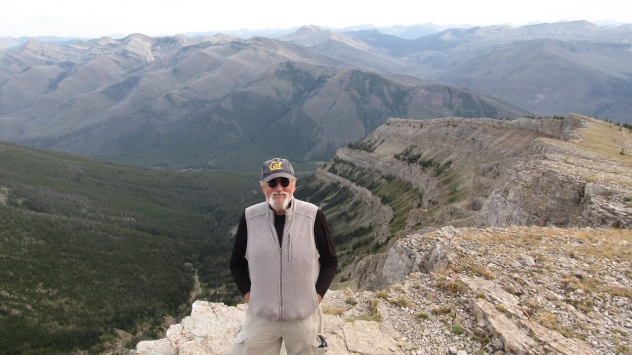 A man standing with large mountains behind him.