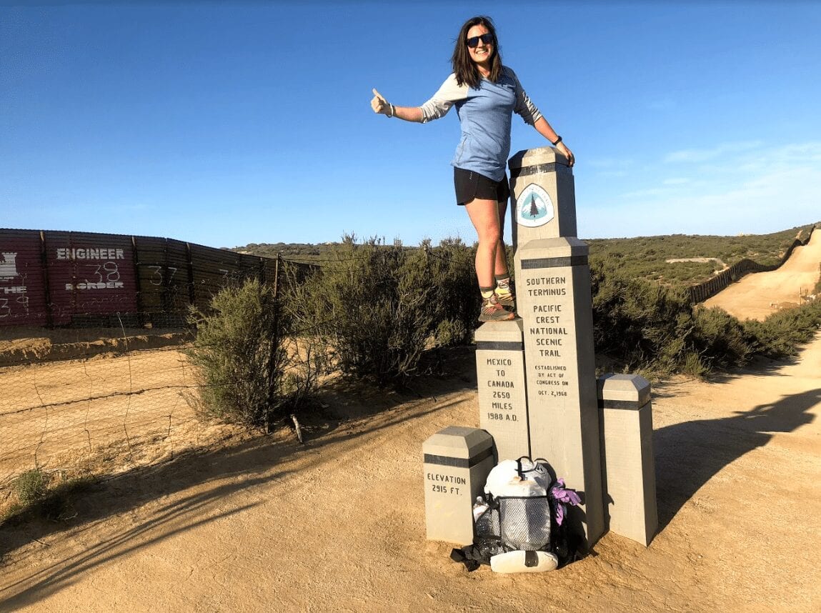 A woman stands on the southern terminus of the Pacific Crest Trail.