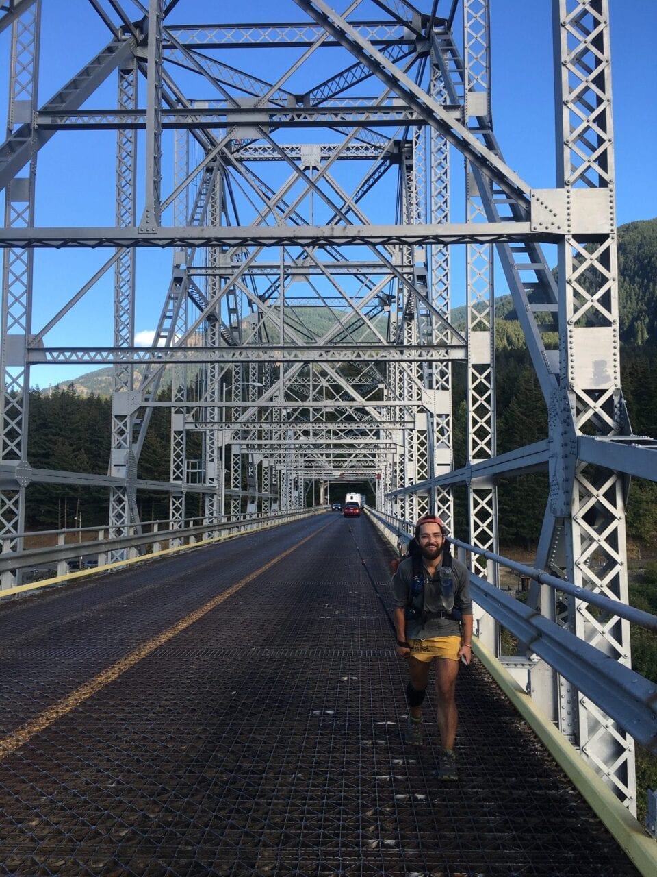 A hiker walking across a bridge.