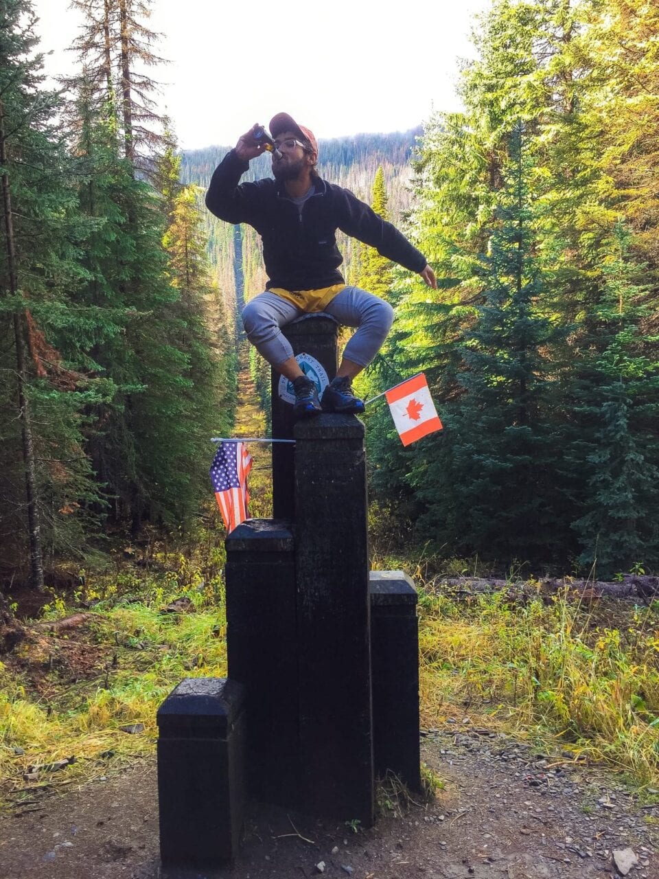 A hiker sitting on the top of the northern terminus for the Pacific Crest Trail.