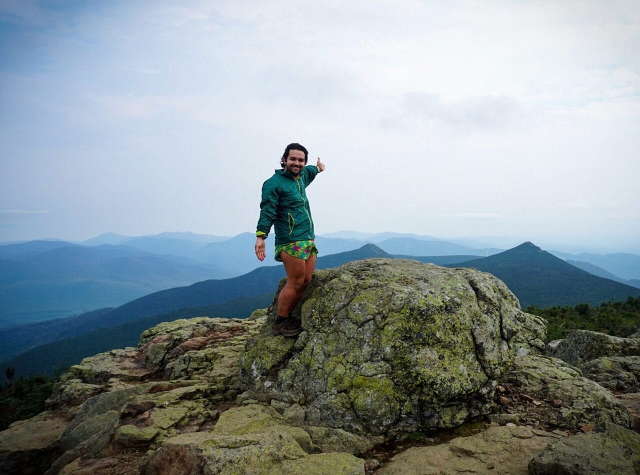 A man standing on a rock with a mountain in the distance.