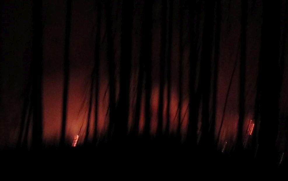 Fire blazes in the distance at night.